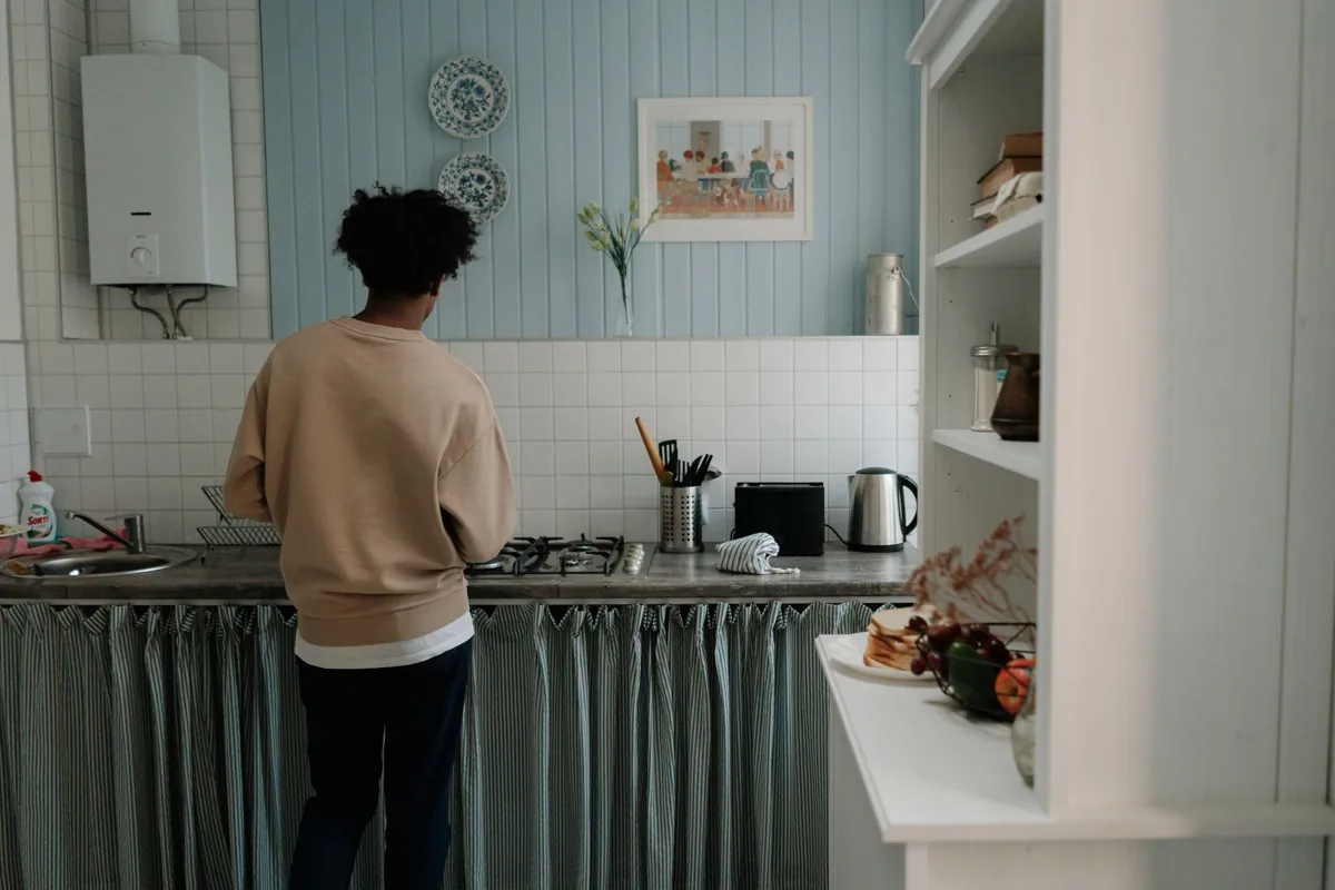 A man with afro hair cooking alone in a stylish, serene kitchen setting.