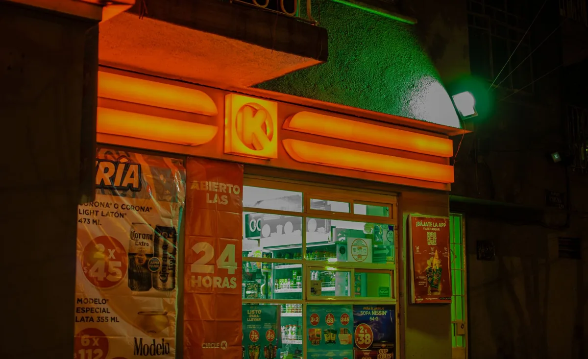 A brightly illuminated convenience store with neon lights at night, showcasing vibrant colors and signage.