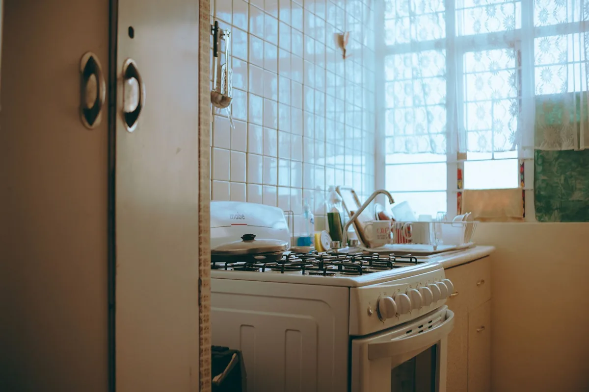 Warm-toned vintage kitchen with stove, tiled walls, and window light creating a homely atmosphere.