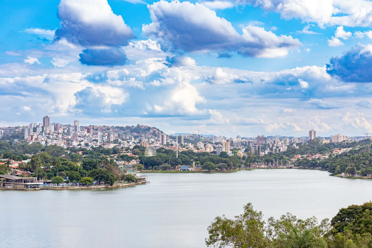 Stunning panoramic view of Belo Horizonte skyline over a serene lake under a vibrant sky.